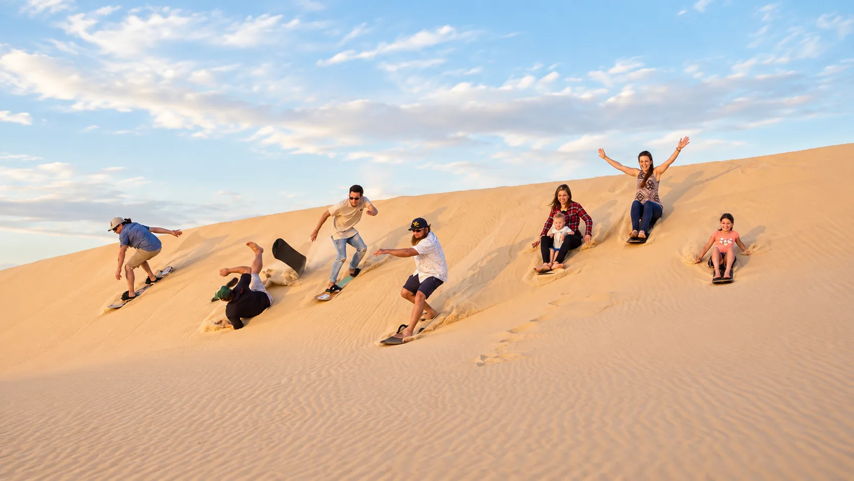 Group sandboarding on sandy dunes